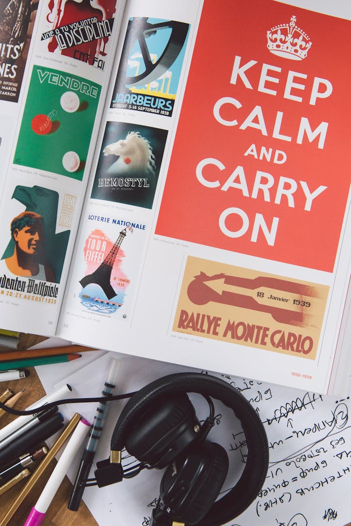 Discover creativity with an open book showing vintage posters, surrounded by artistic supplies and headphones.